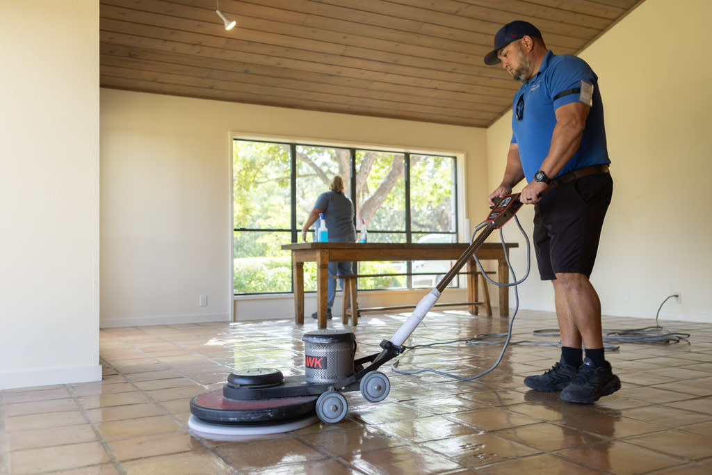 Professional deep cleaning service polishing a tiled floor with a machine indoors.