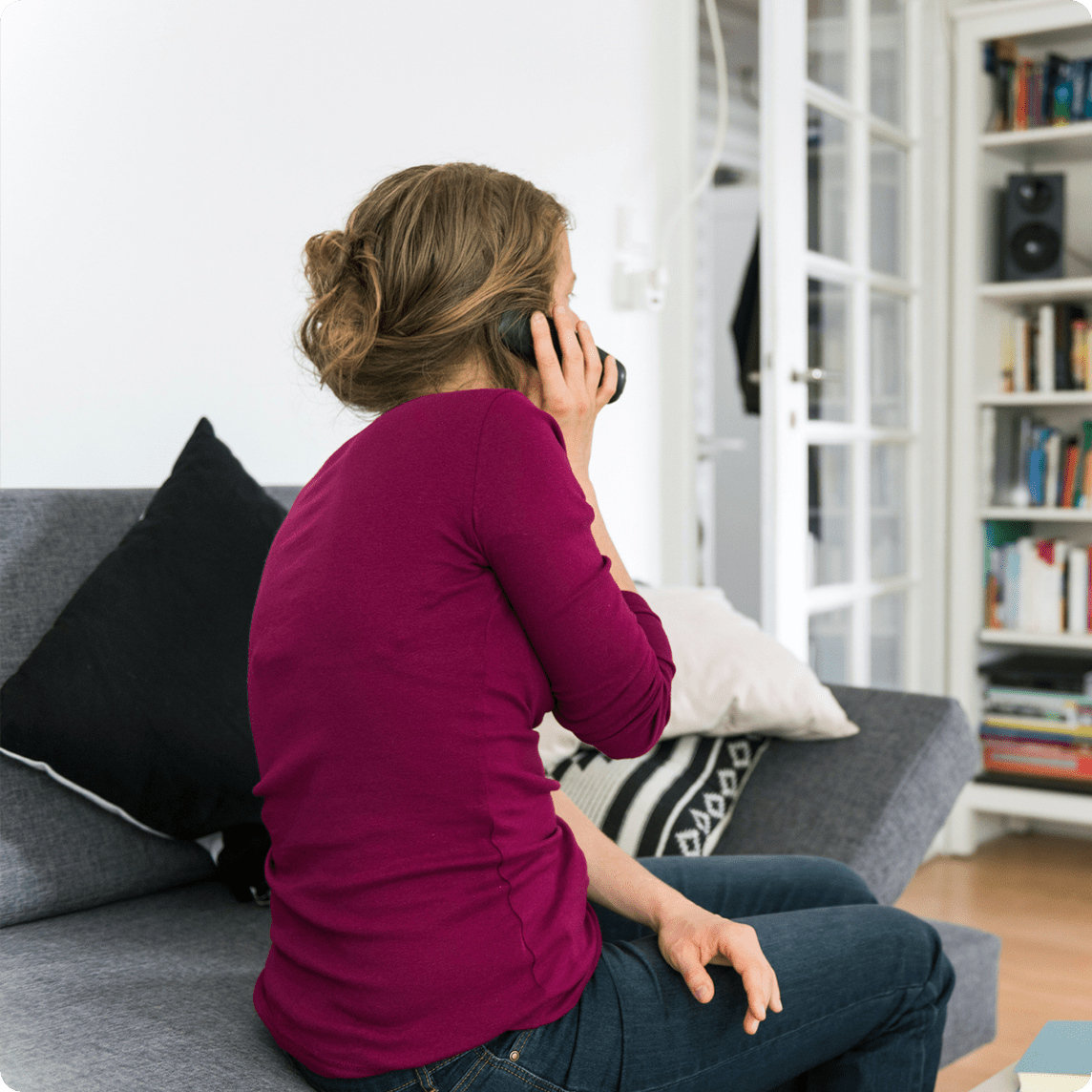 woman talking on landline phone with back turned to camera