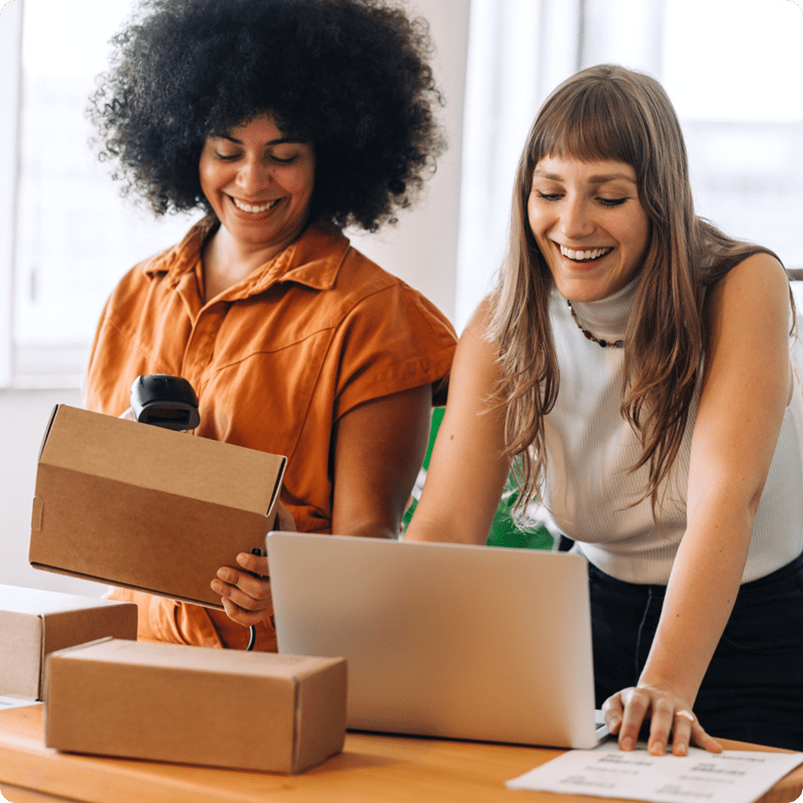 Two store employees working to fill an order with a laptop and package.