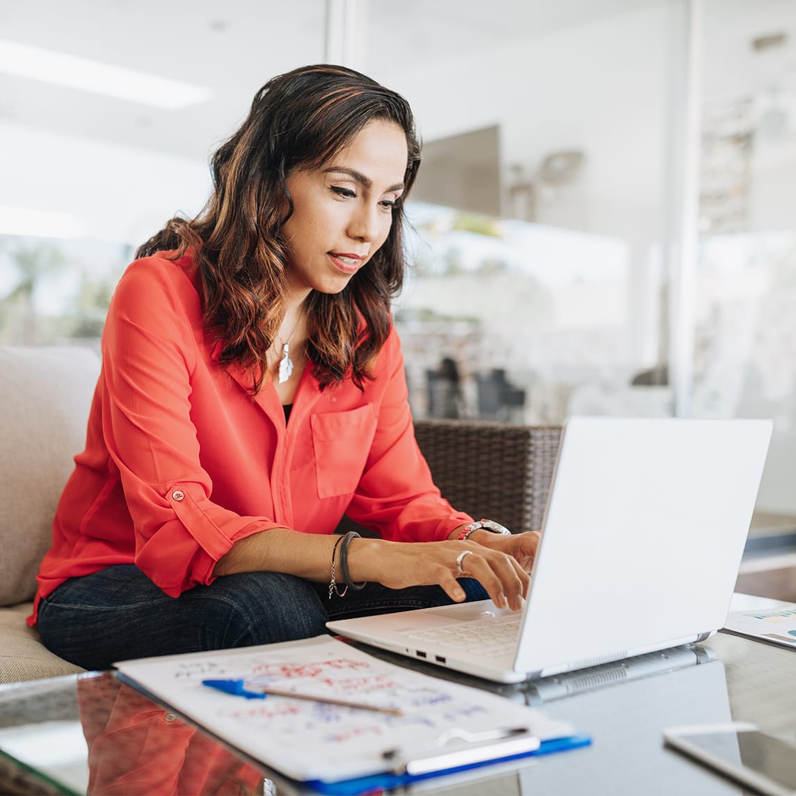 Woman on couch typing on laptop