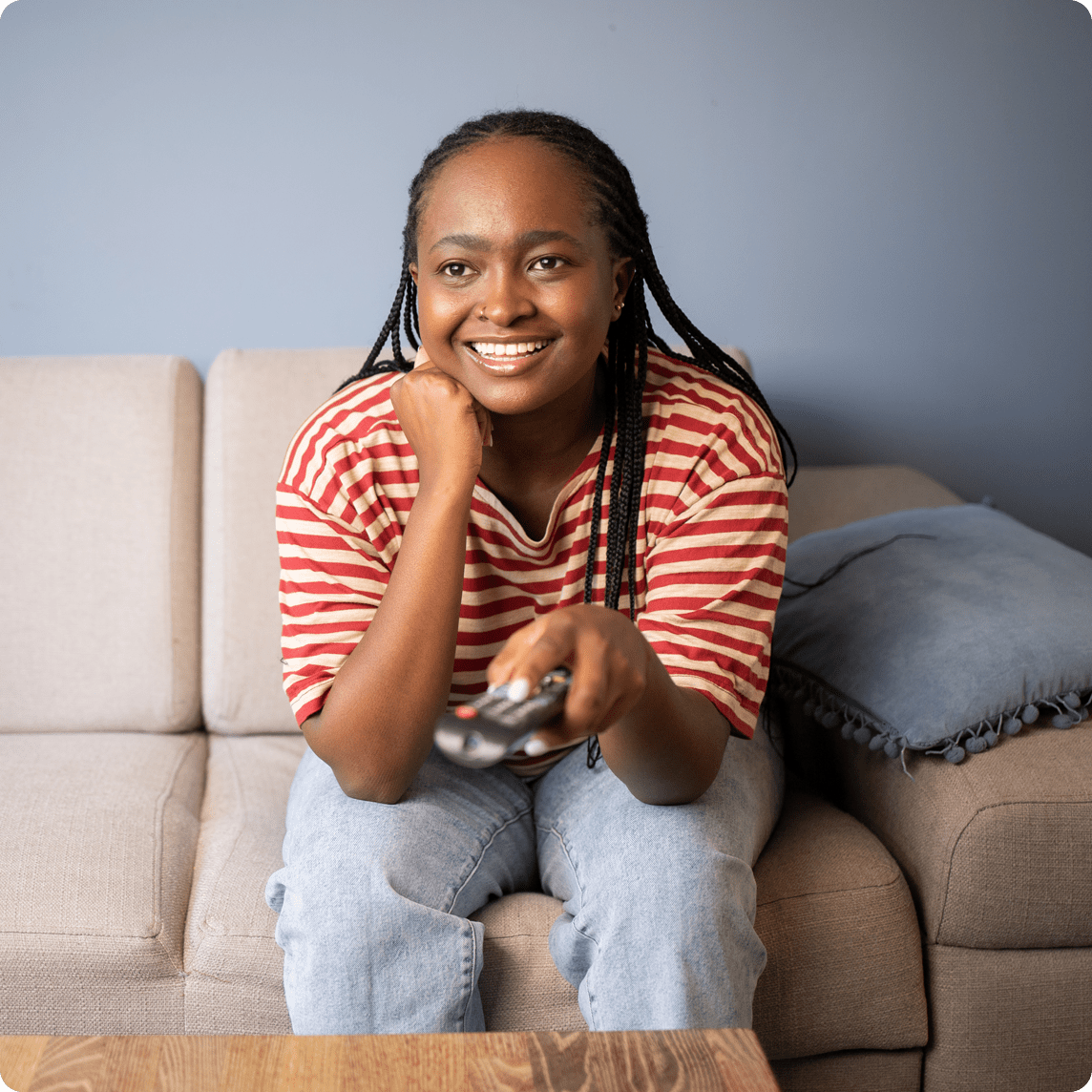 Chica con camisa a rayas rojas, viendo la televisión en el sofá. Girl in red striped shirt, watching tv on the sofa.