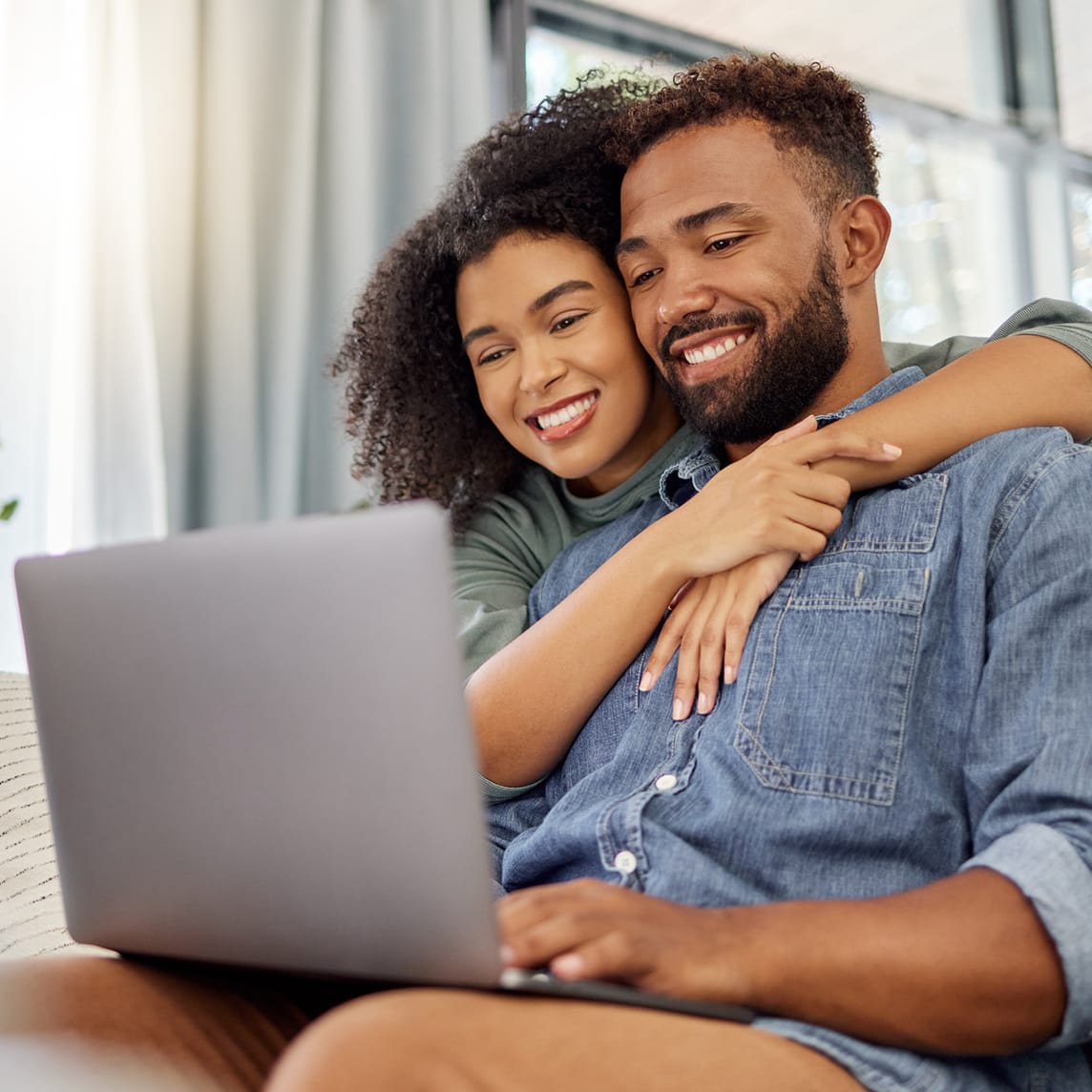 Couple looking at tablet while sitting on couch