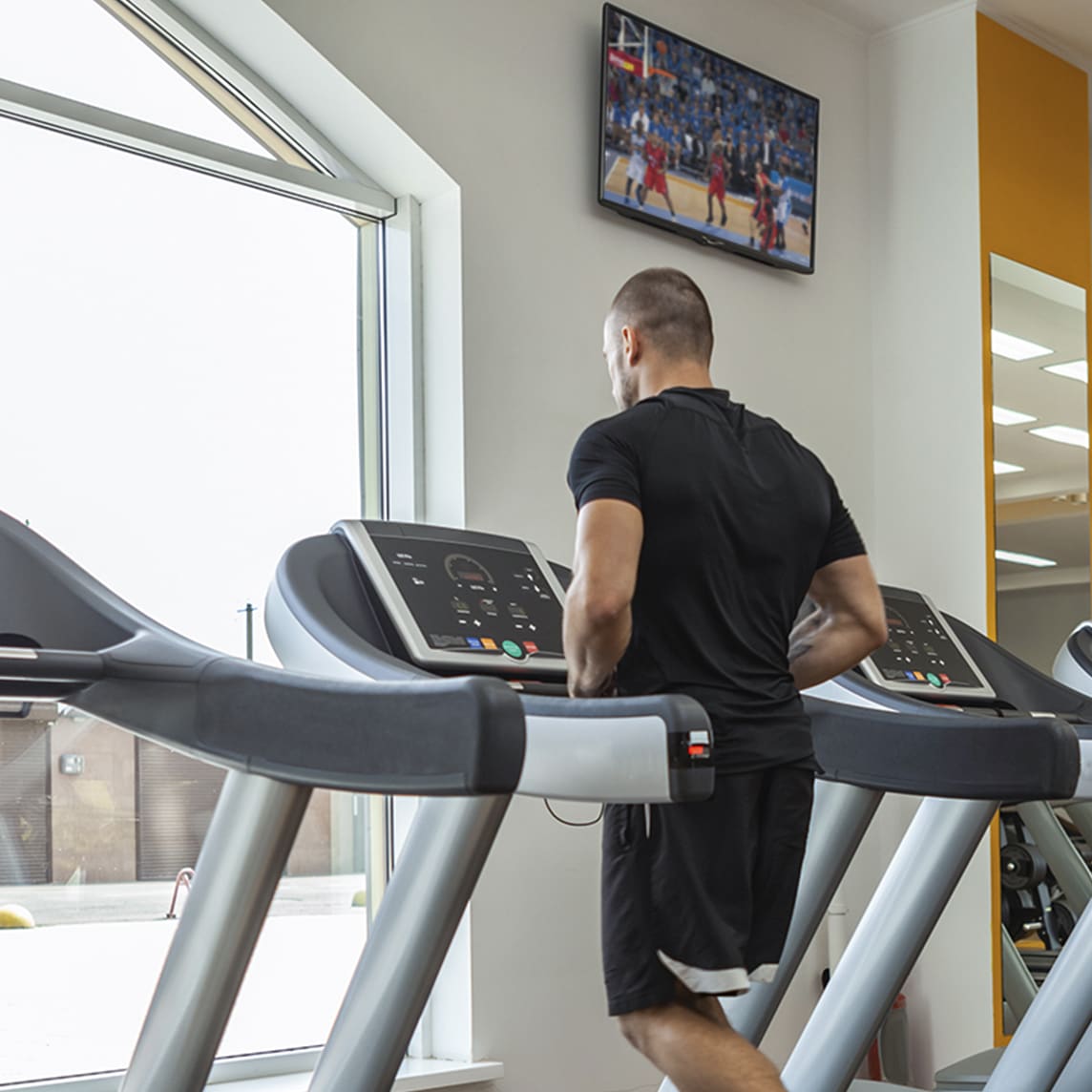 Man at gym watching TV while running on treadmill