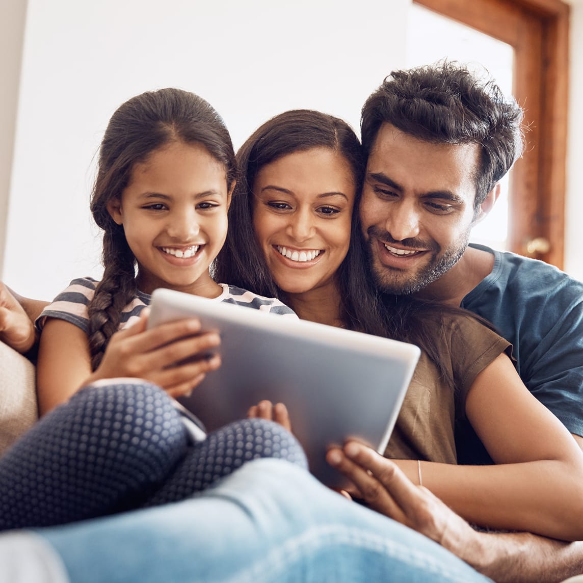 Family cuddling on the couch watching a show on a tablet