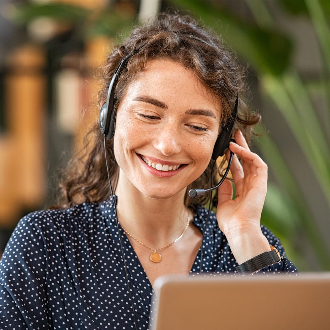 A customer service rep talks on headset while smiling and looking at computer screen