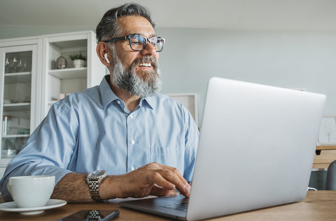 Man sitting at kitchen table looking at laptop