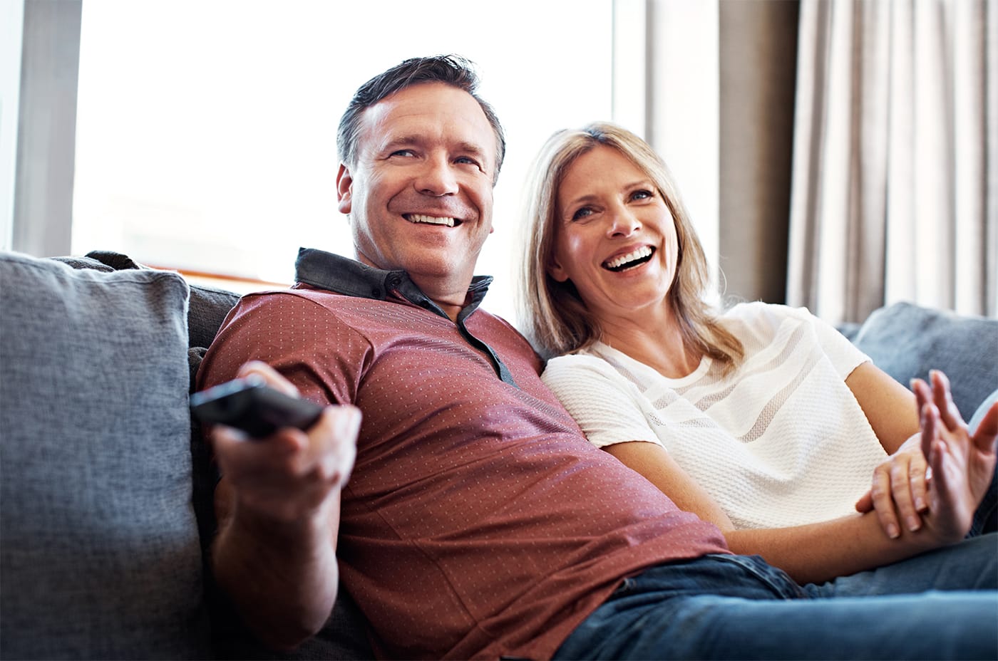 couple on couch using tv remote control