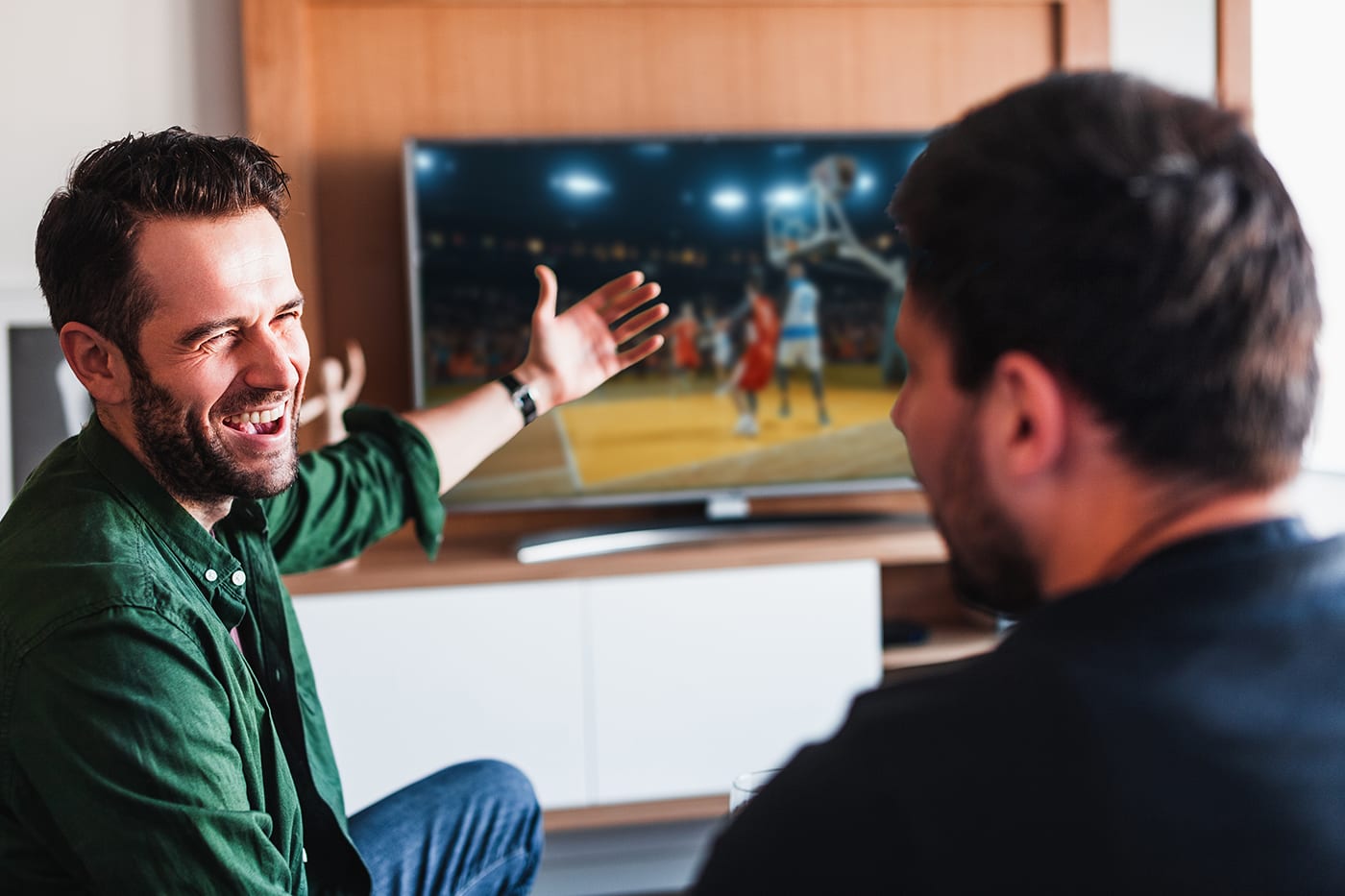 Two friends watching basketball on the tv