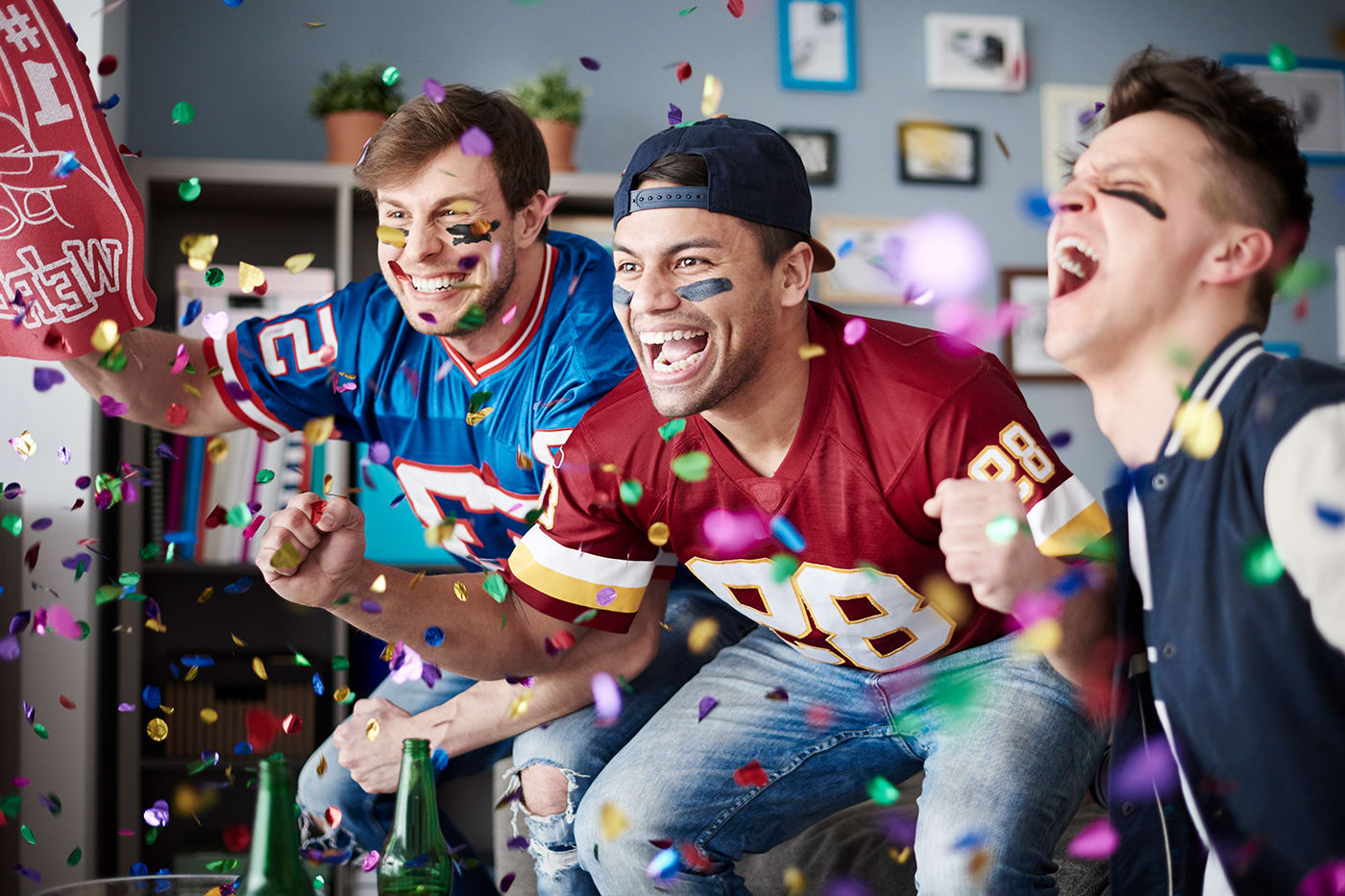 friends dressed in sports attire cheering at tv