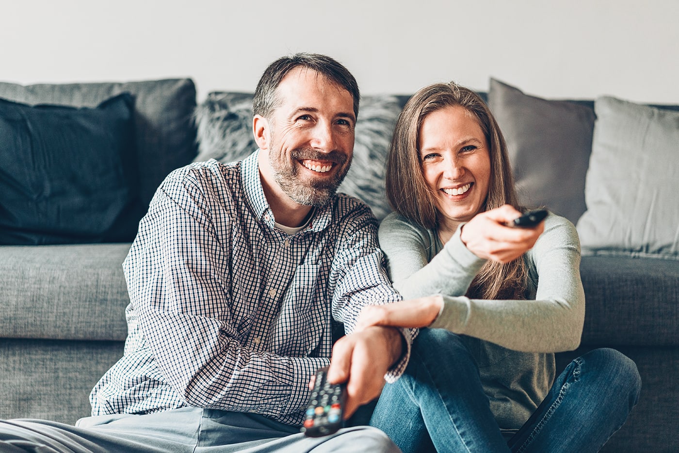 couple on couch fighting over tv channel