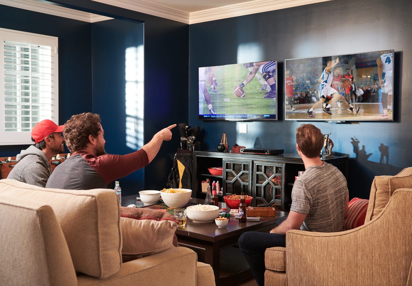 guys watching sports on two T.V.'s in a living room