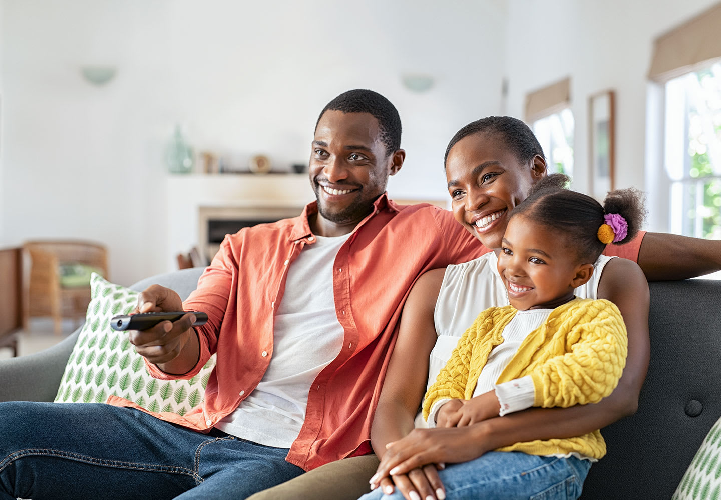 Husband, wife and daughter sitting on sofa watching TV