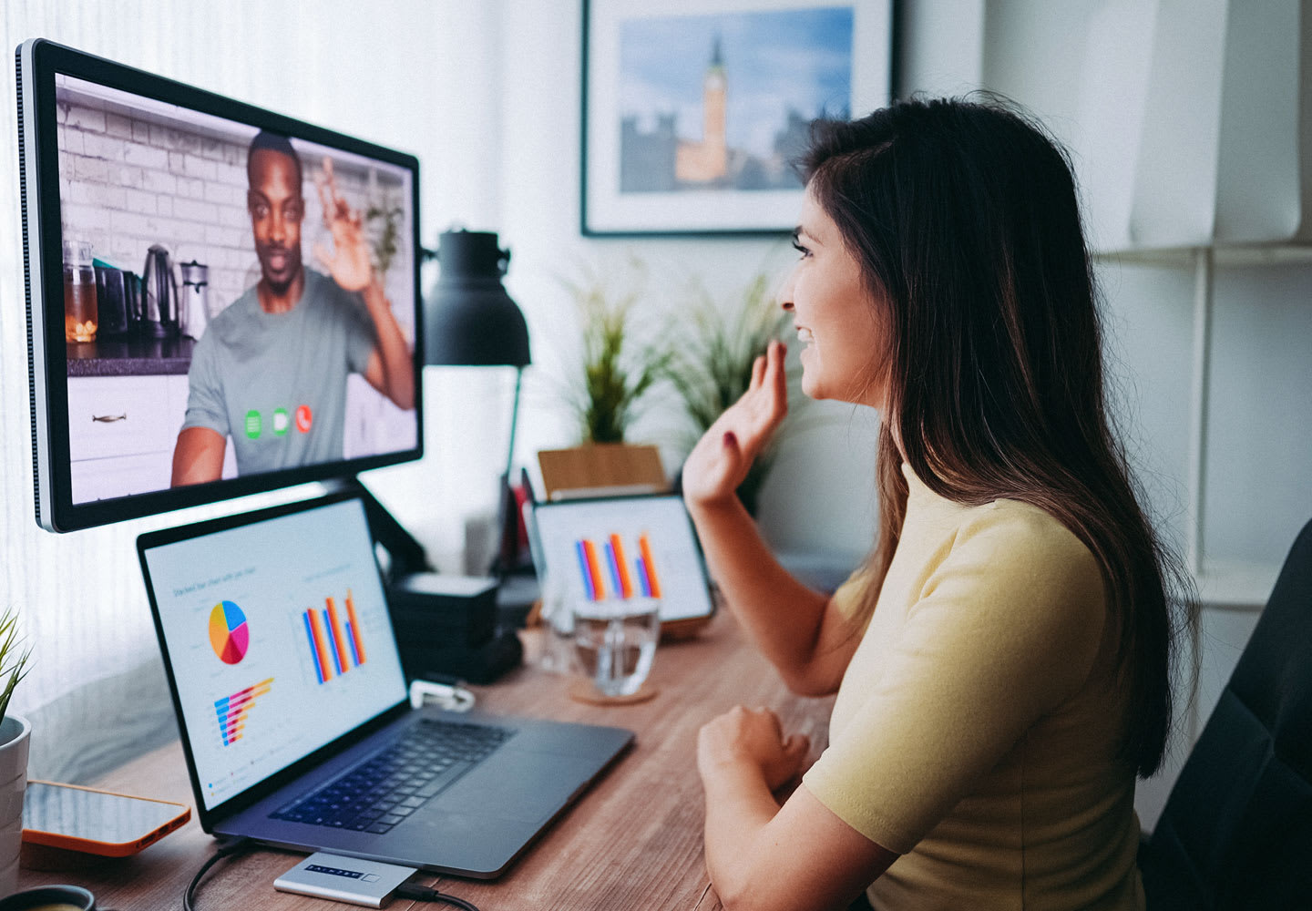 Woman sitting at a desk, talking on a zoom call with a male co-worker