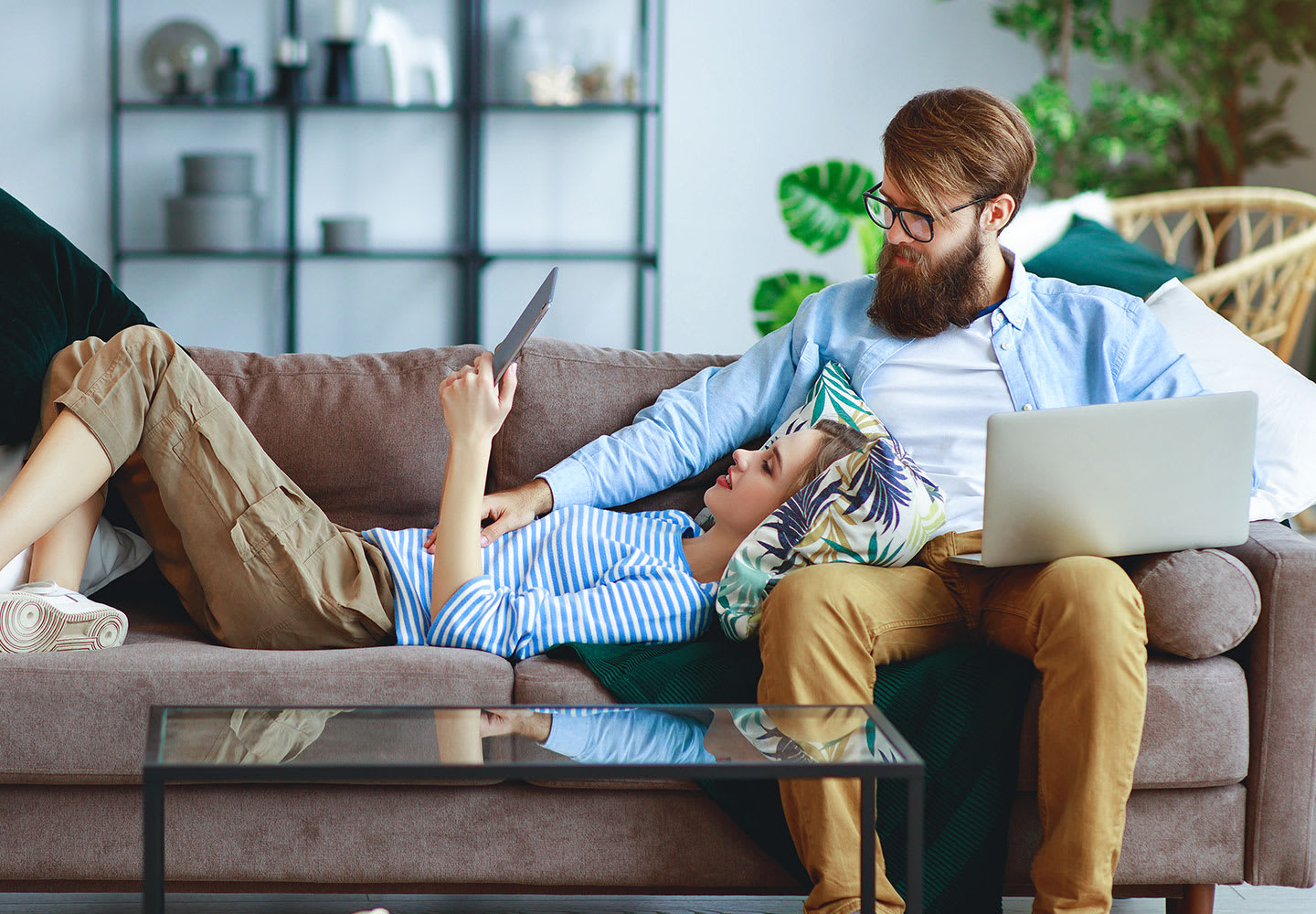 A couple sitting on a sofa looking at internet devices