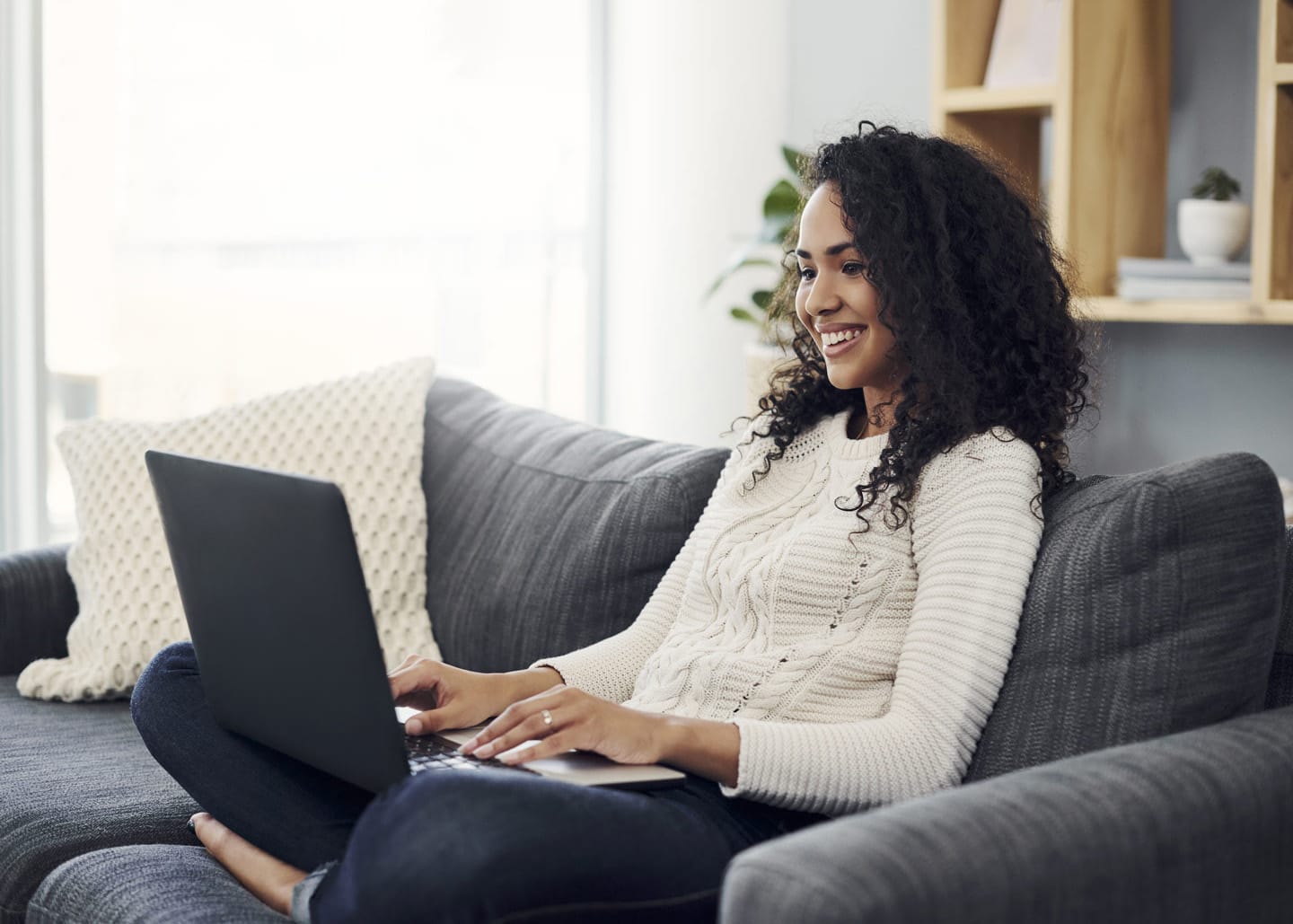 Woman on her laptop in a cozy living room using CenturyLink internet