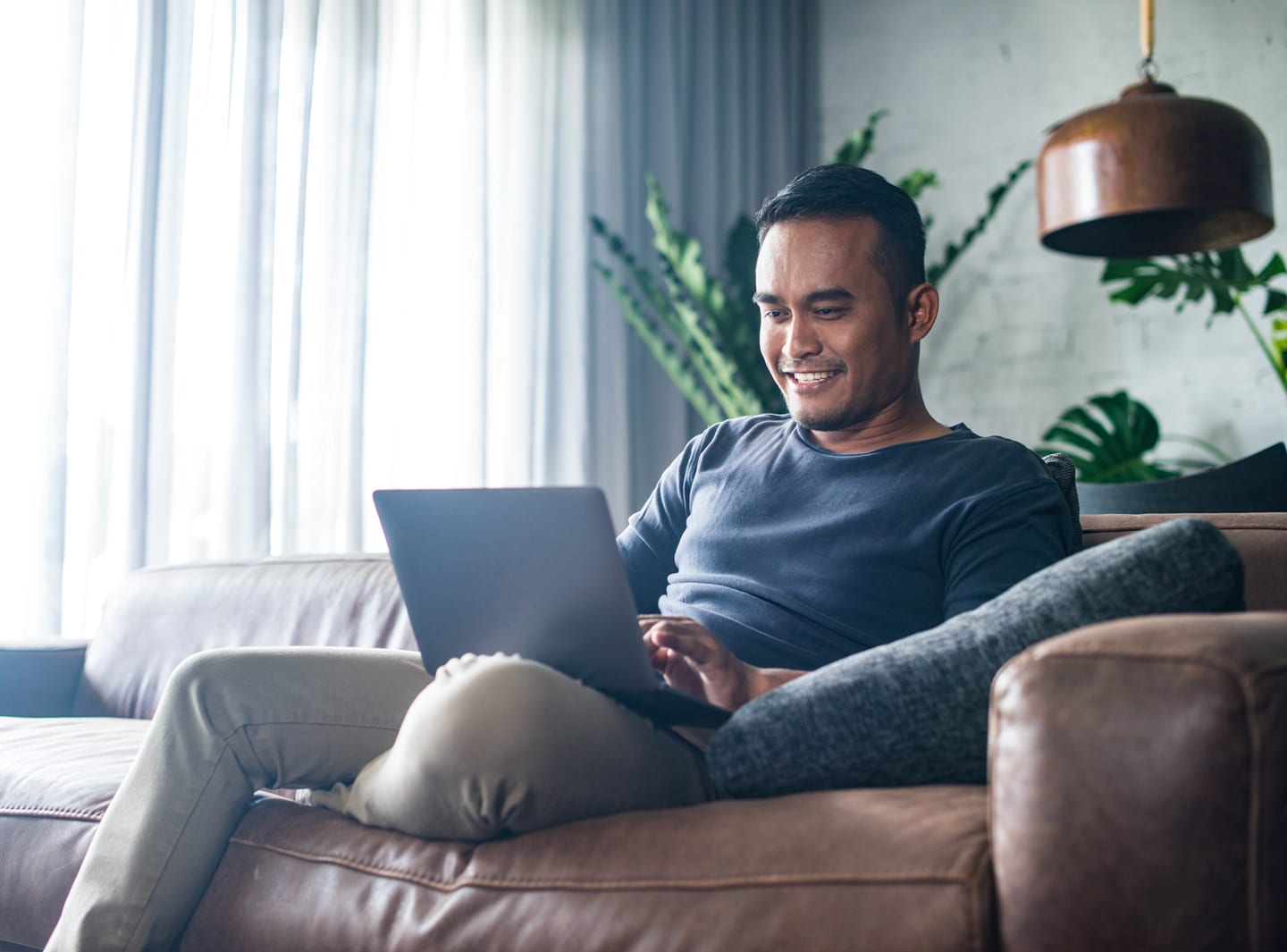 Man sitting on a leather couch using CenturyLink internet