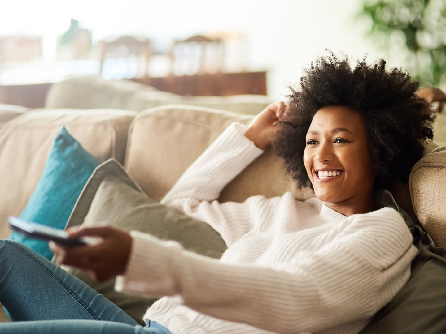 Smiling Girl watching TV on her sofa.