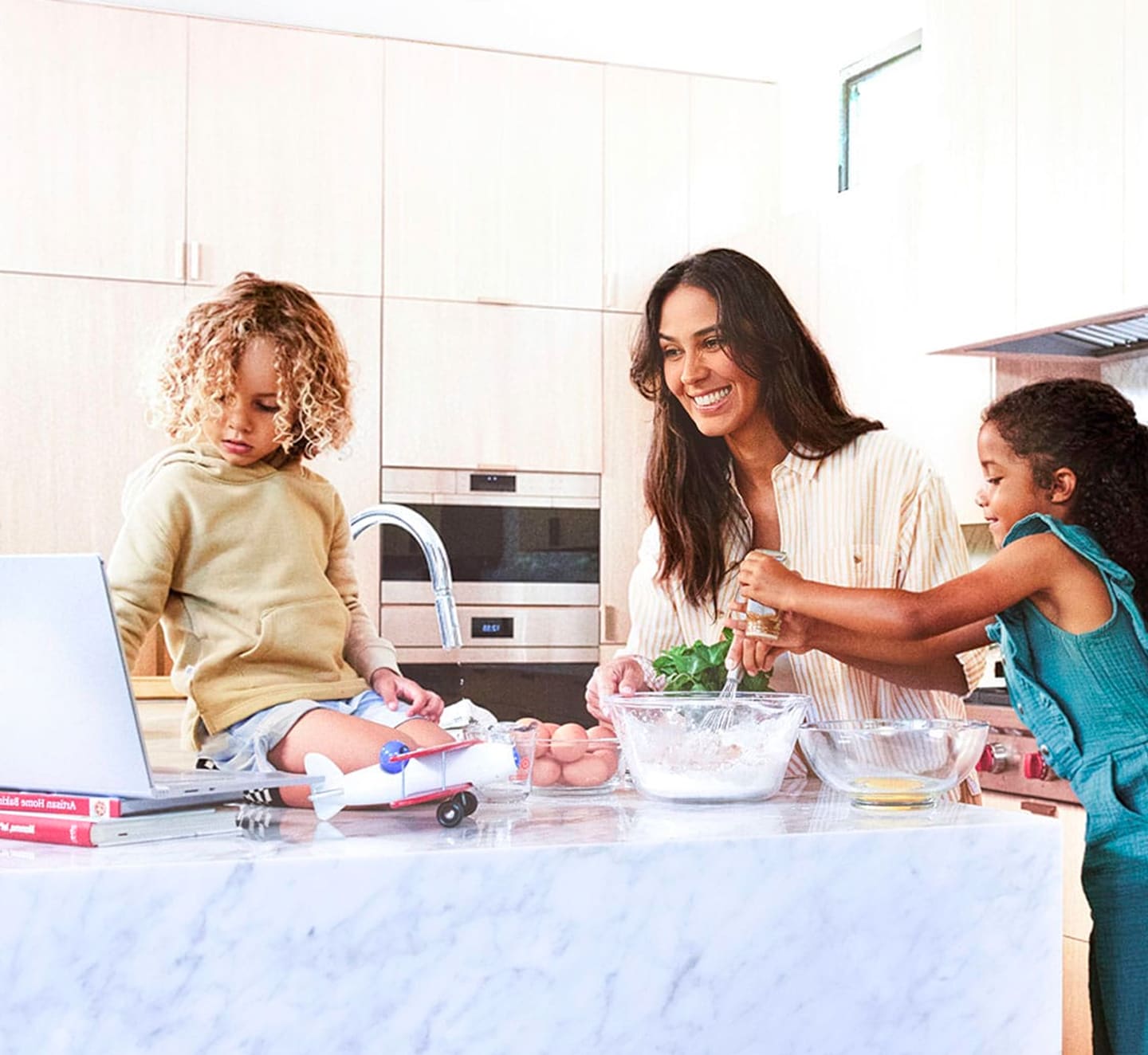 A mom and two children look up a recipe on a laptop in the kitchen using Frontier internet.