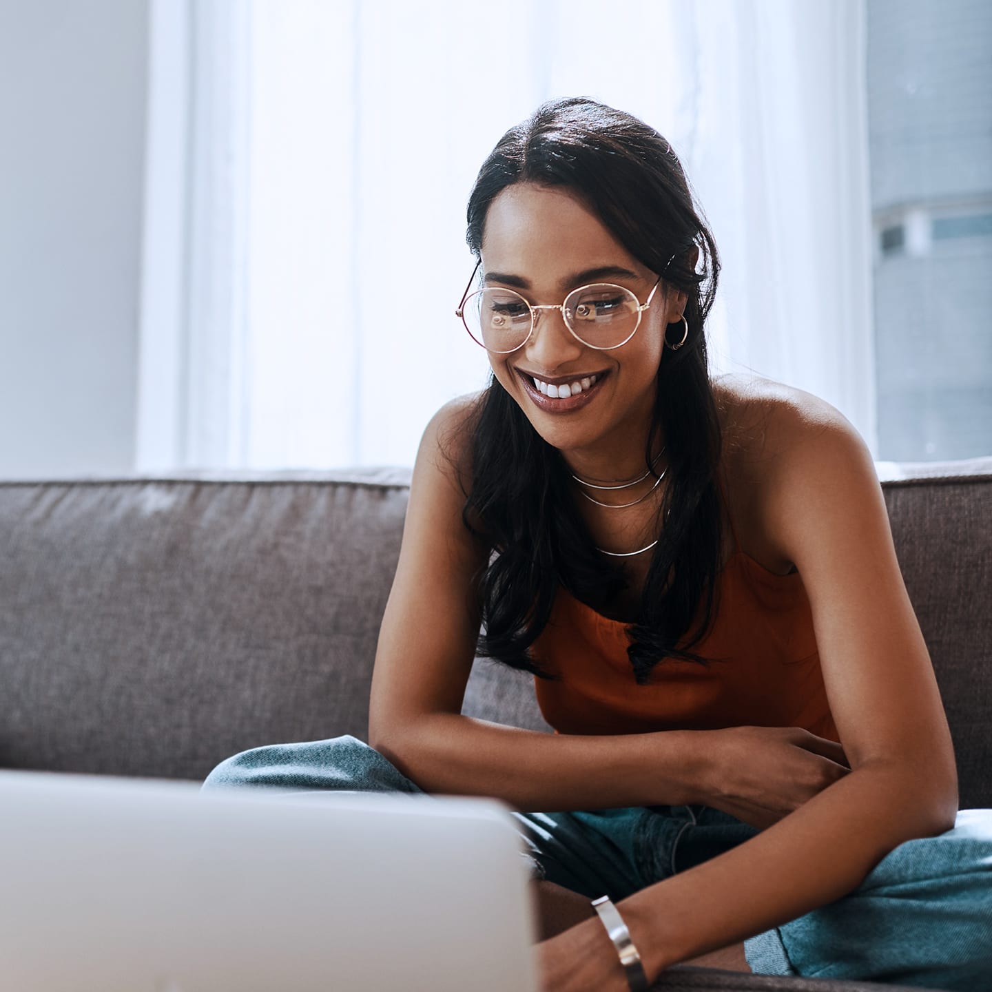 Chica con gafas sentada en el sofá y usando internet