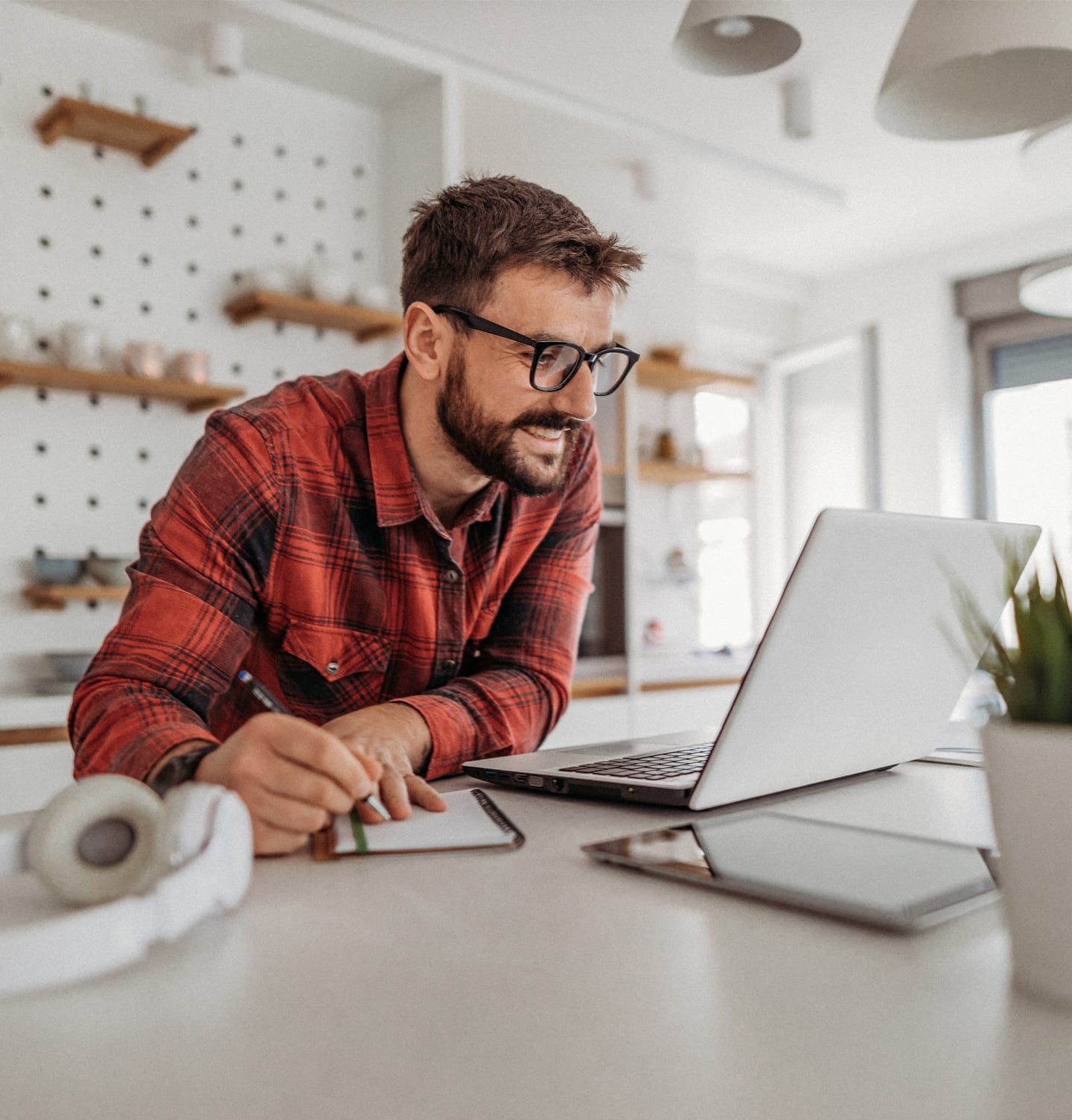 Man in red plaid shirt using the internet on his laptop