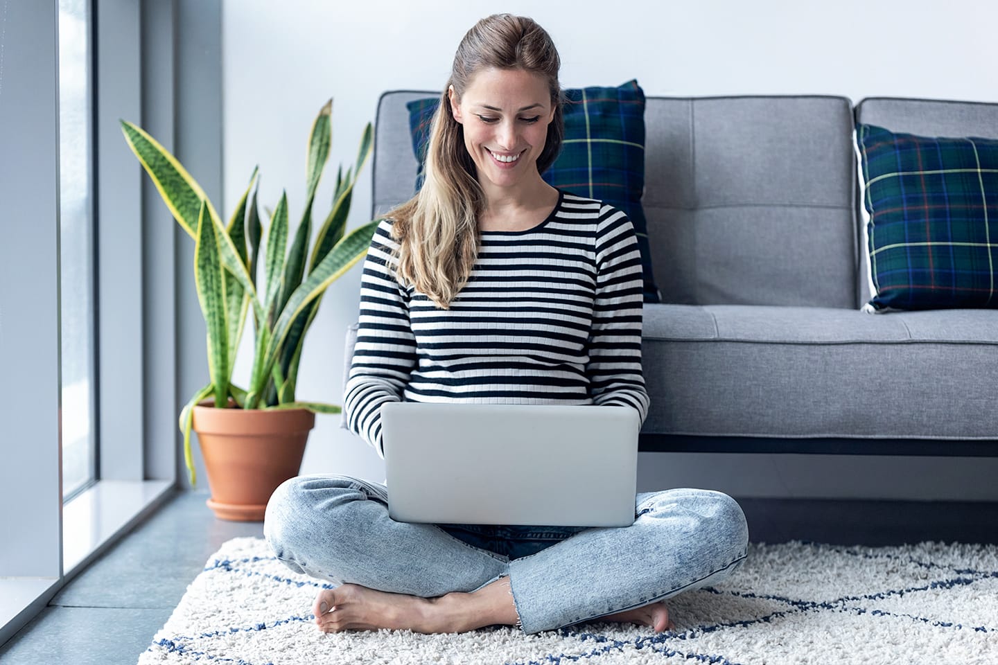 Woman sitting cross-legged on the floor using her laptop on CenturyLink internet