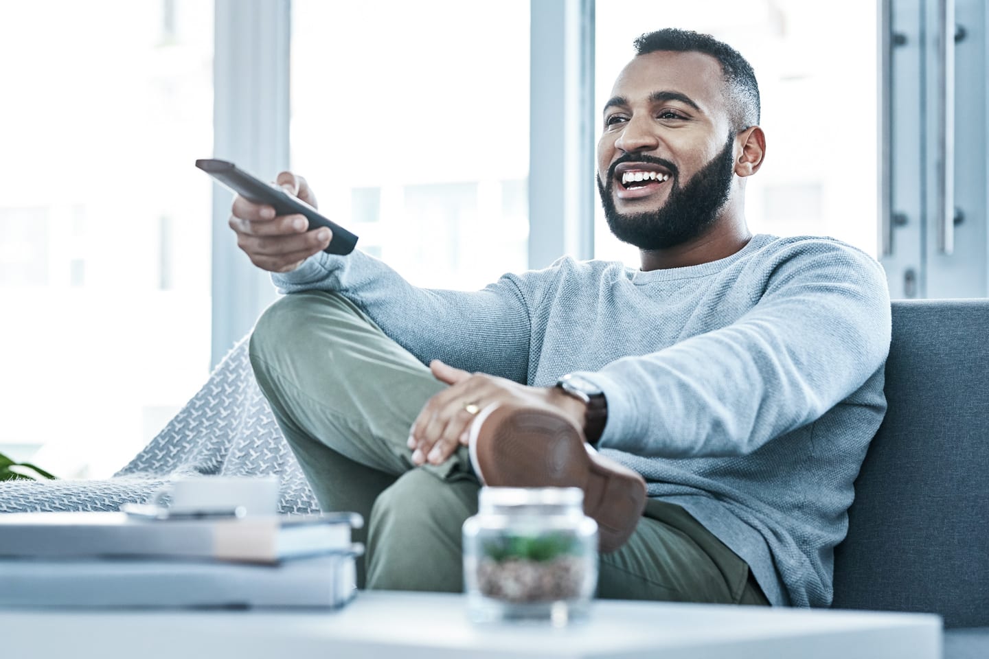 man on the couch pointing his remote control at the TV