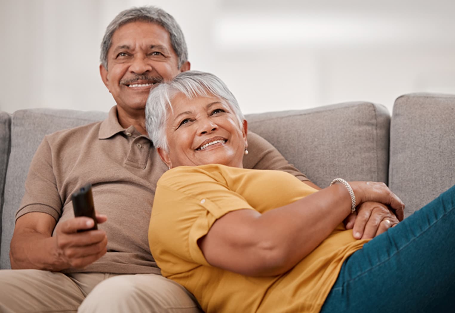 A senior couple embraces while watching television.