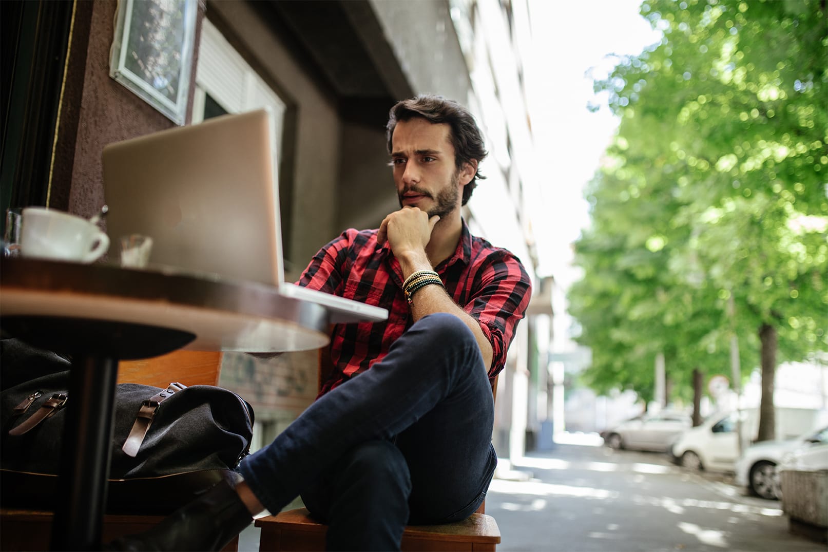 man watching tv on laptop at outdoor cafe