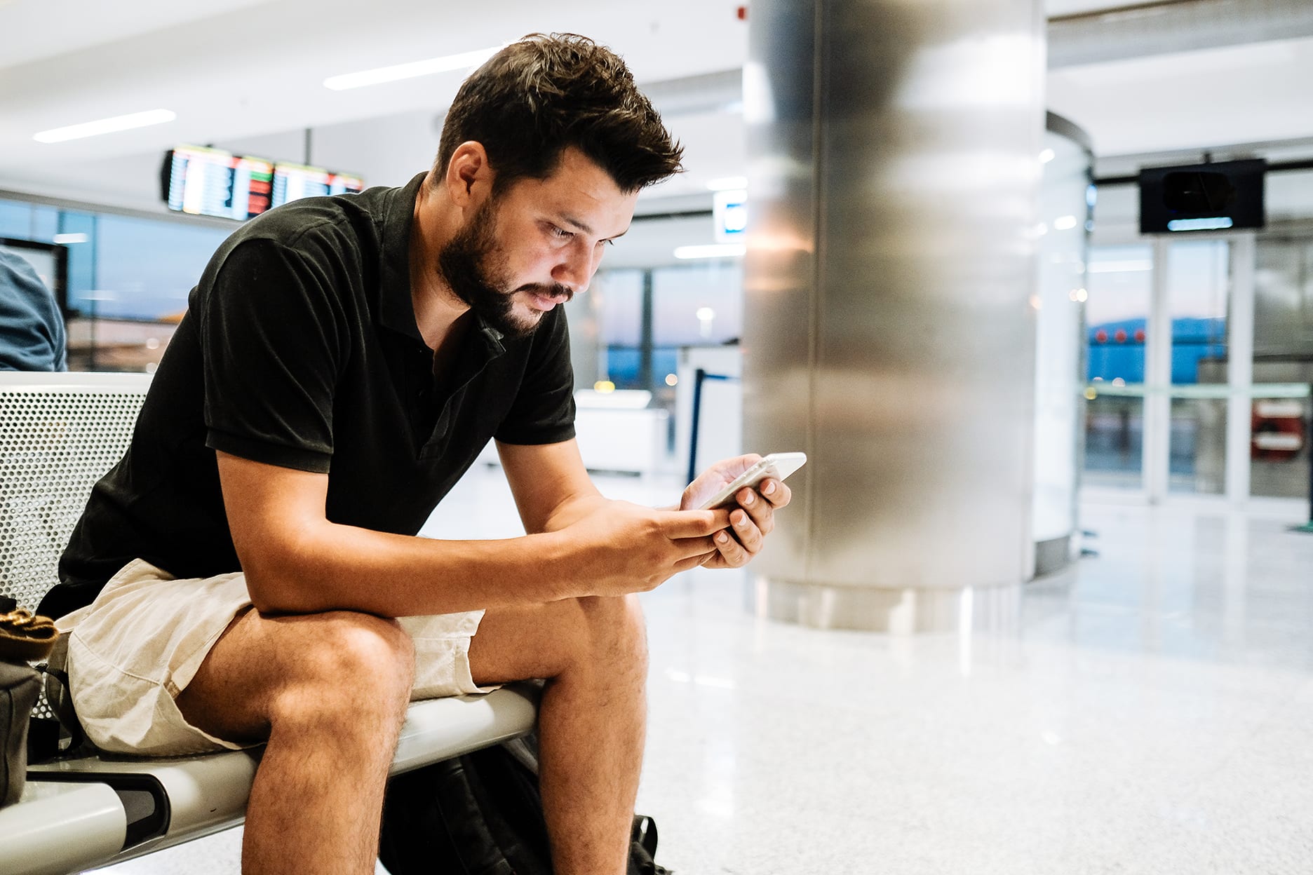 man watching phone in bus station