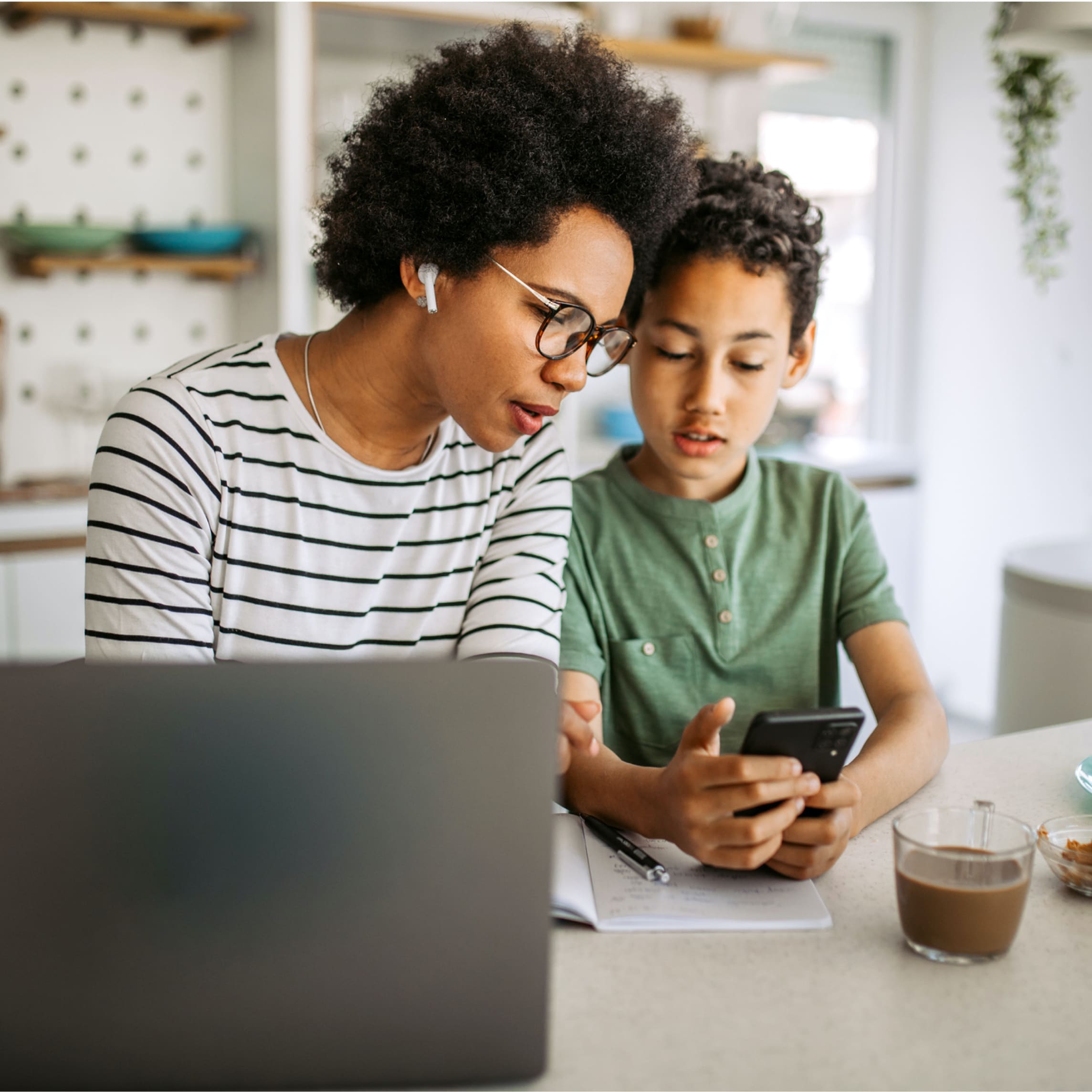 Mother and son using laptop and phone together.