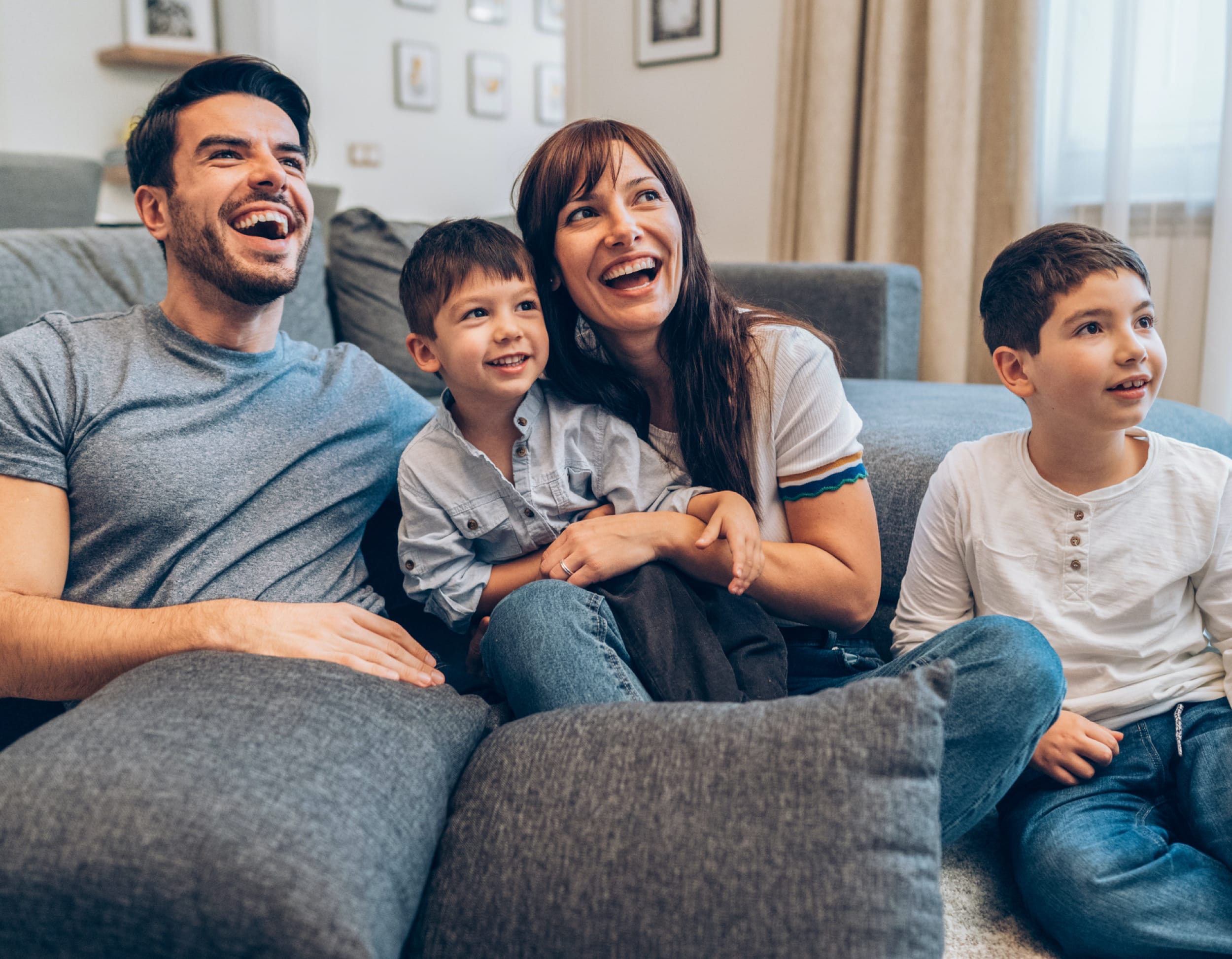 Happy family sitting on couch watching a movie.