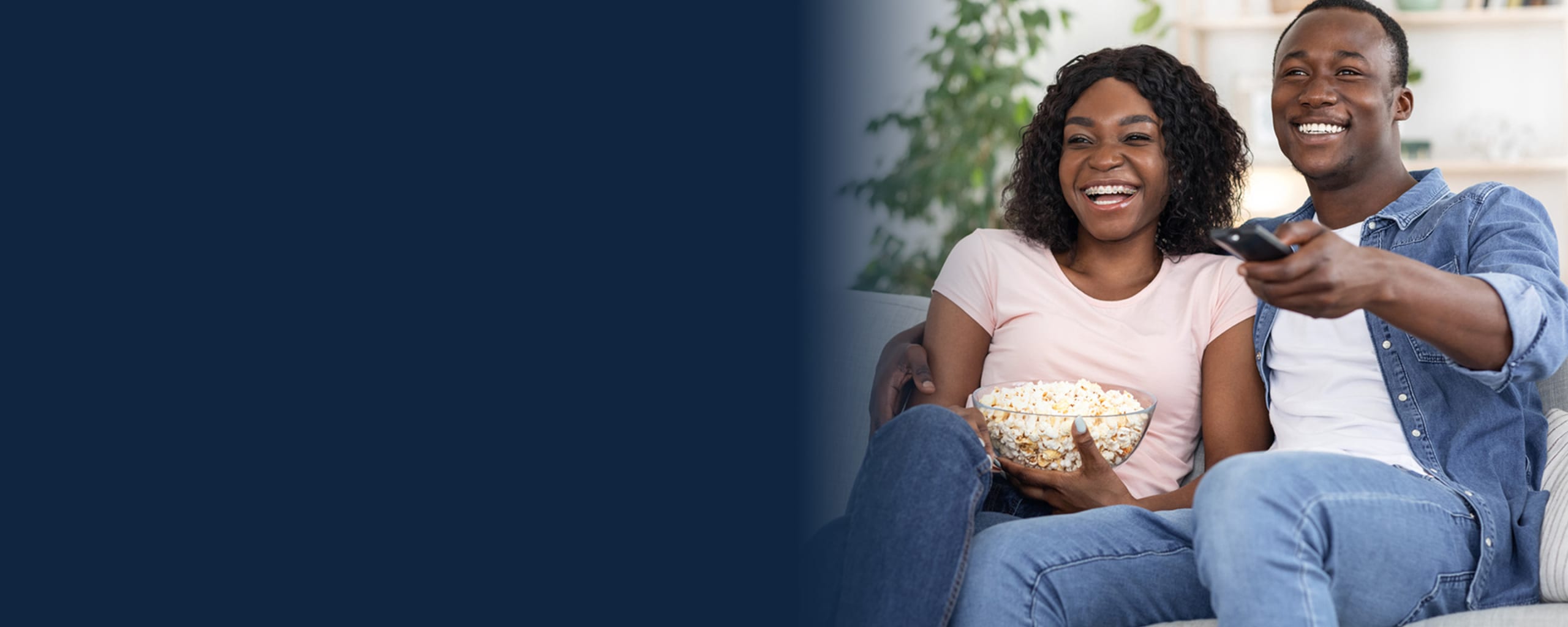 Couple watching tv while eating some popcorn.