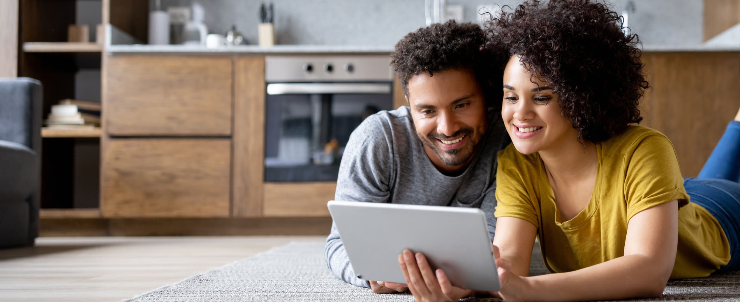 Couple laying on the floor looking at a tablet