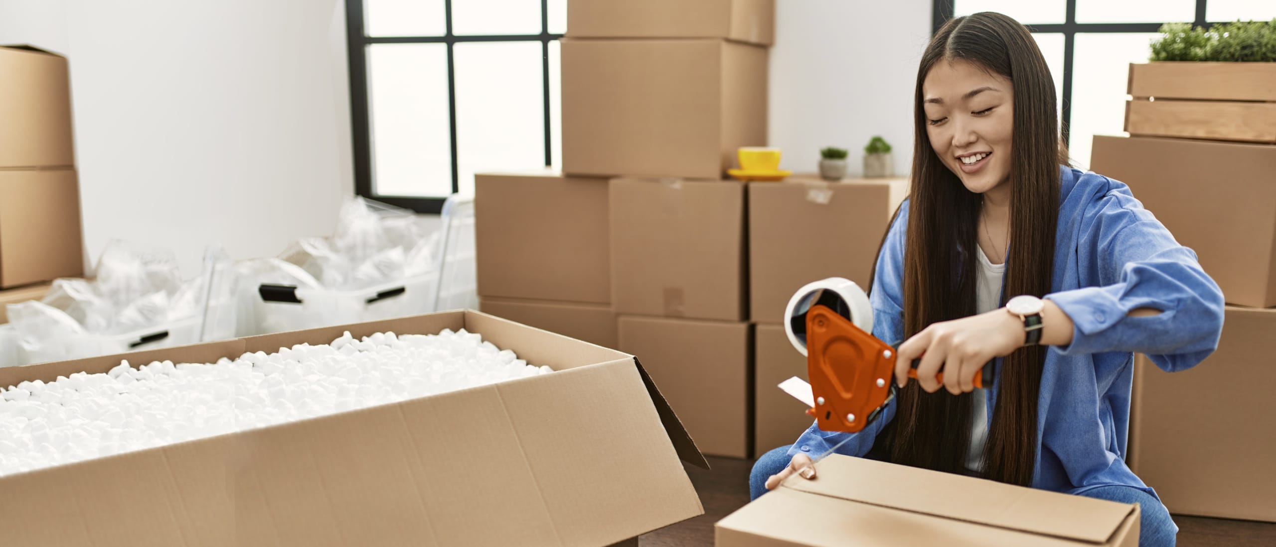 Girl packing up her things and taping boxes.