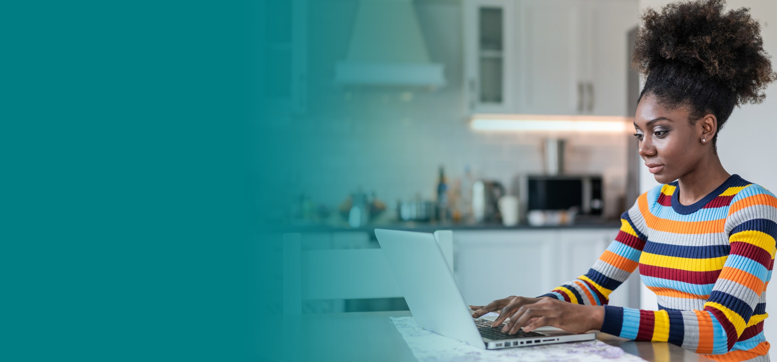 woman typing on laptop on kitchen table