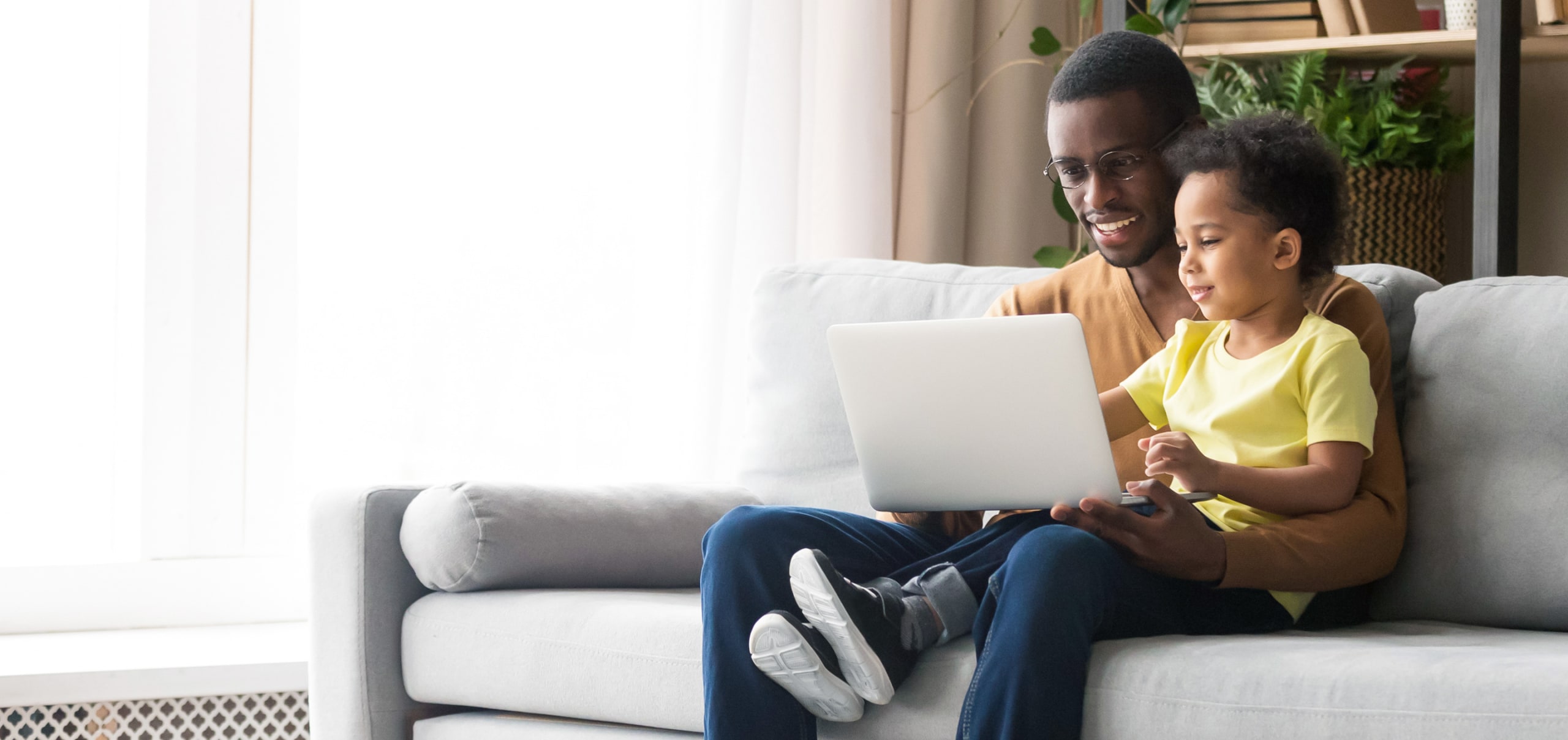 father and son on couch with laptop