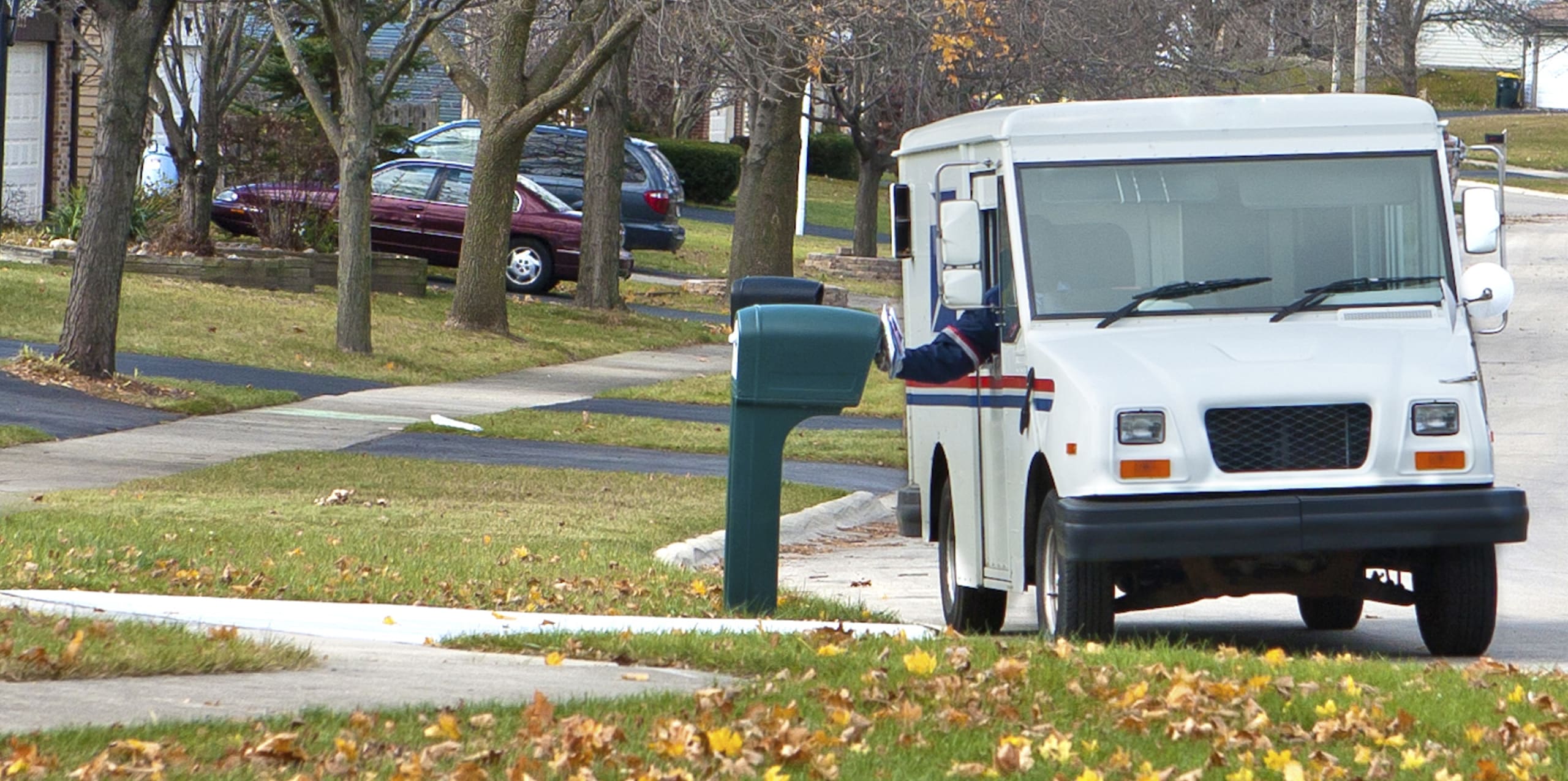 US mail truck delivering letters to a home mailbox