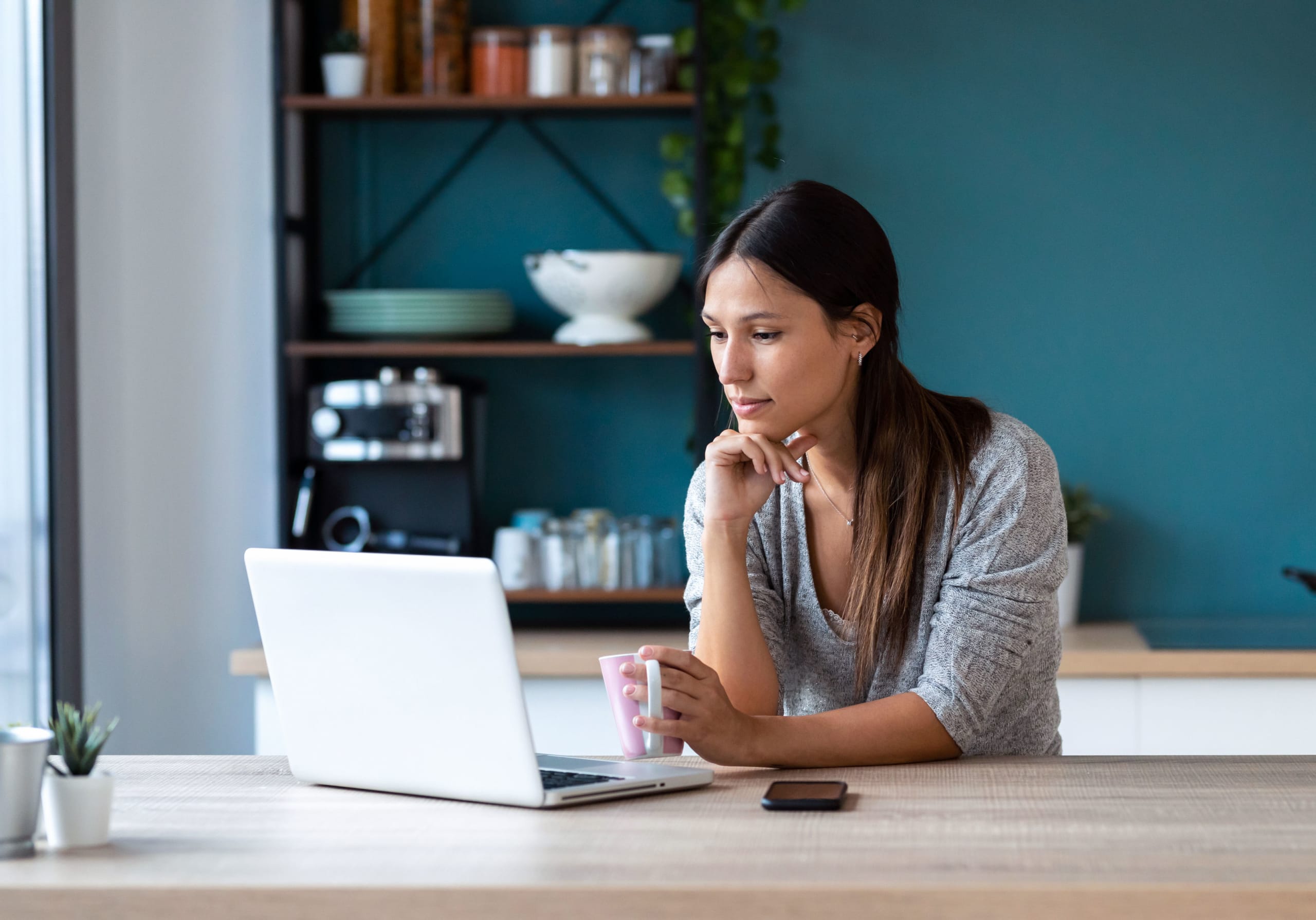 woman watching a show in her kitchen on her laptop using CenturyLink internet