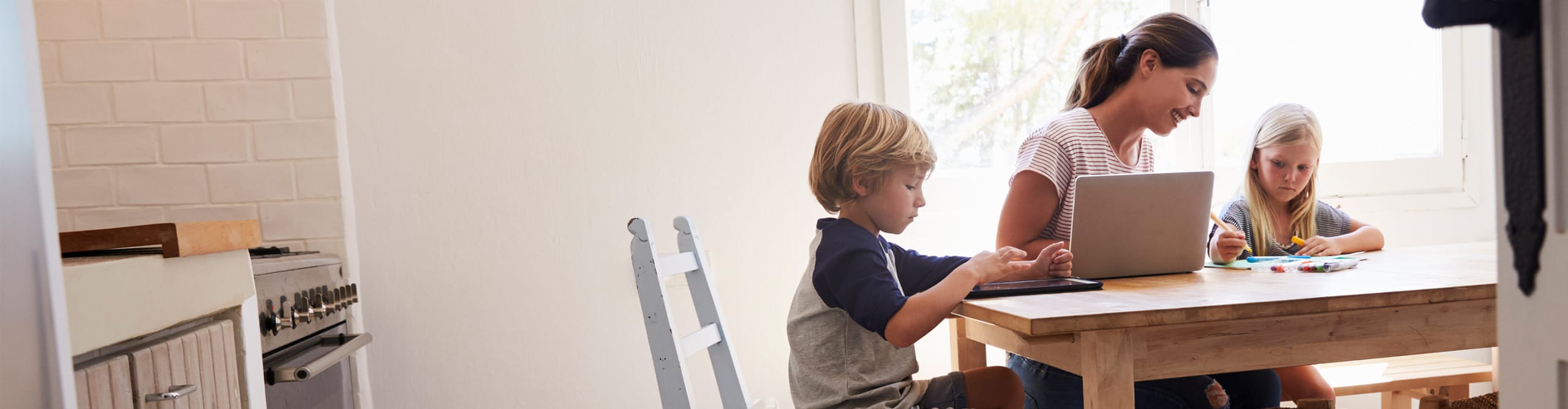 mom and children at kitchen table with laptop