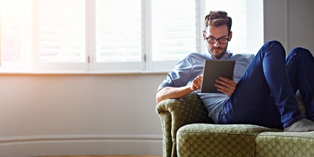 Man sitting on the sofa and enjoying the internet on his tablet