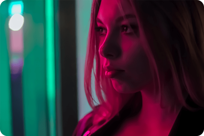 Mujer mirando a lo lejos bajo la brillante luz rosa. Woman looking off into the distance under the glowing pink light.