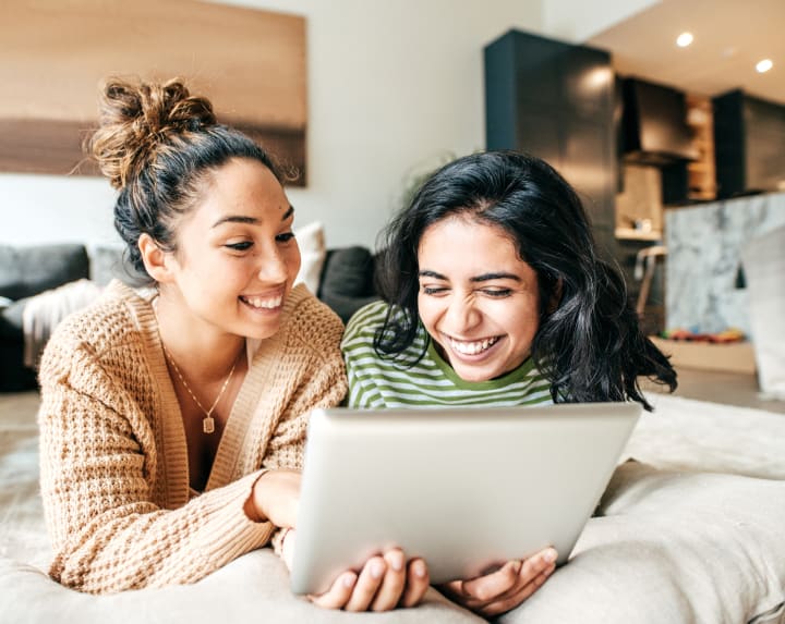 two woman laying down looking at tablet