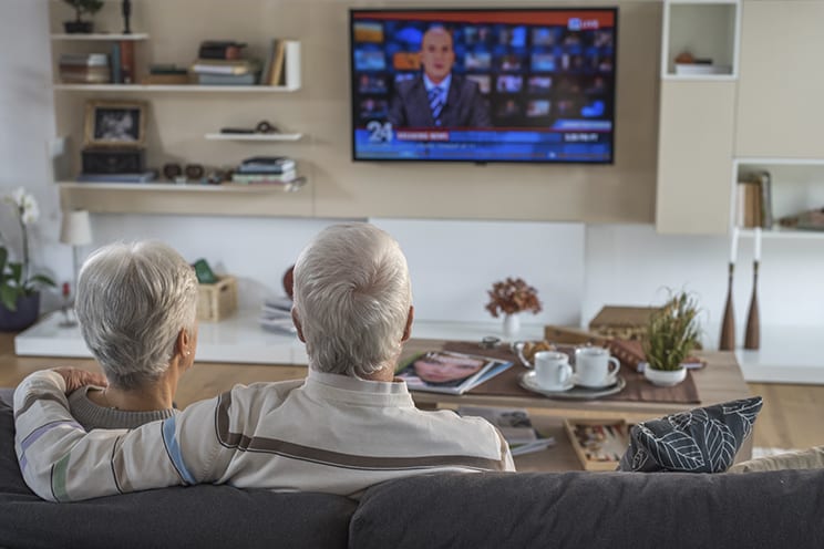 Older couple sitting on couch watching the news