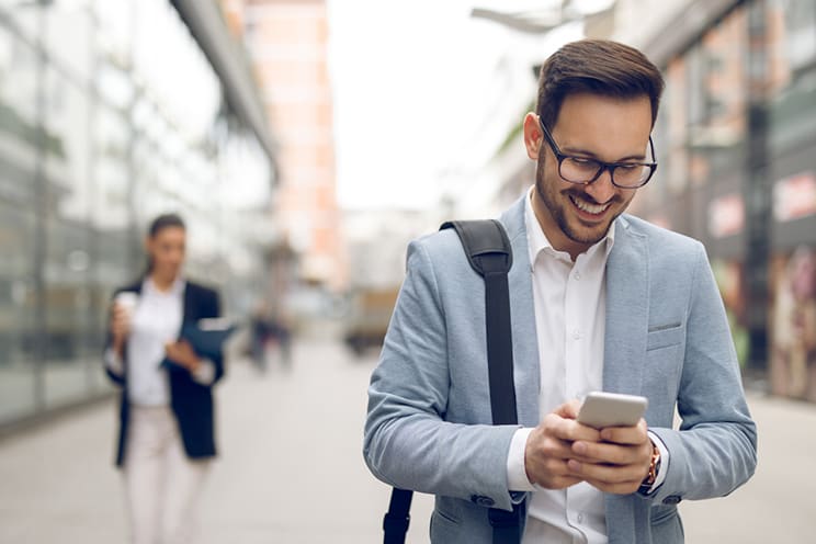 Man in suit walking down street while using phone