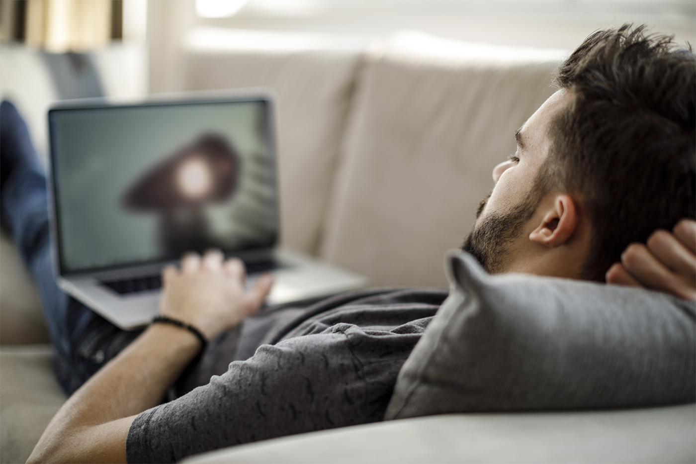 man on couch watching movie on laptop