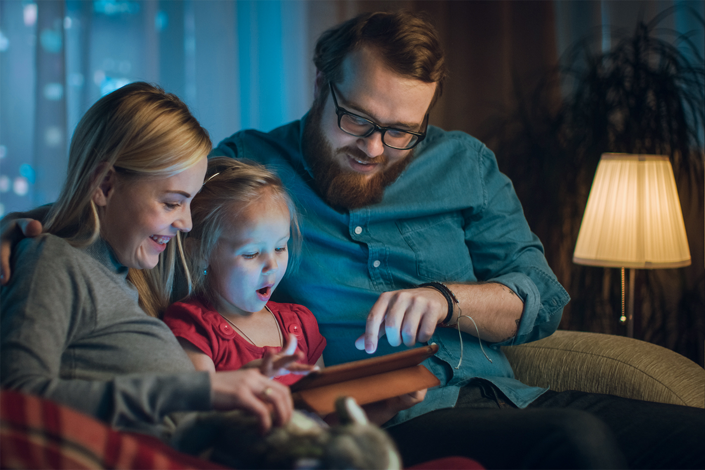 family sitting on couch streaming a movie to their tablet