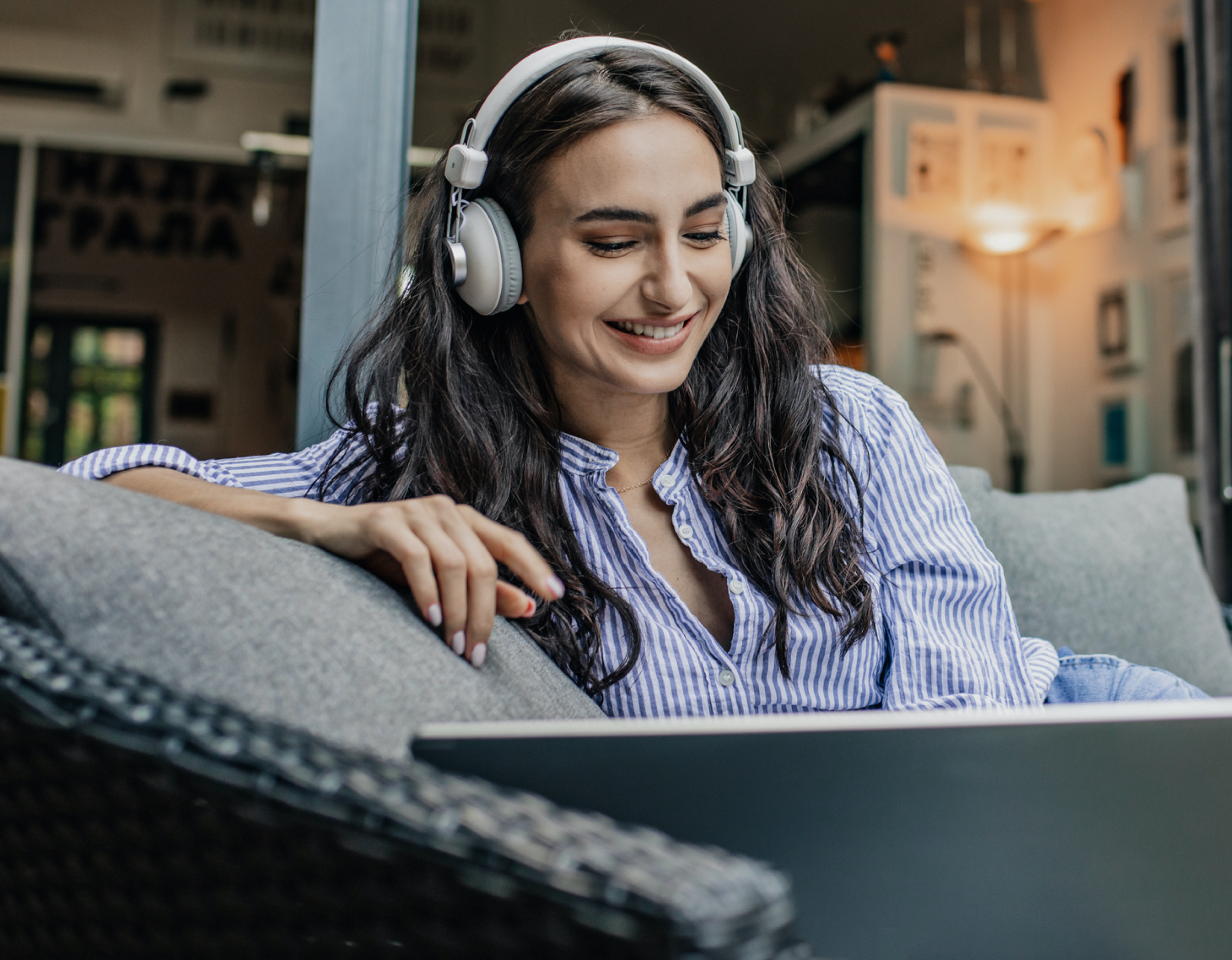 Happy woman lounges on couch with laptop with fast internet.