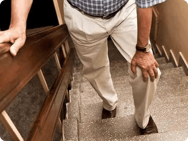 Person holding knee while walking outdoors