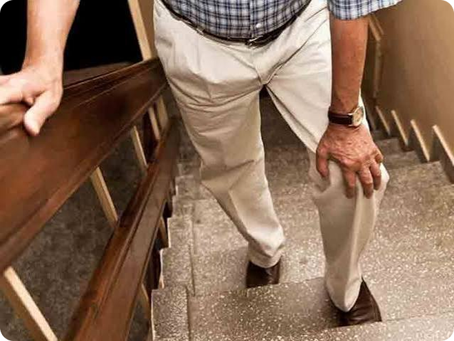 Person holding knee while walking outdoors