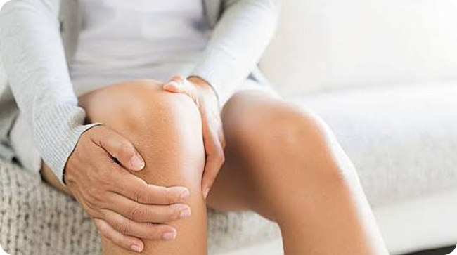 Person holding a painful knee while seated
